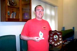 James Byers holding up an award statue and an award shield with names of previous winners.