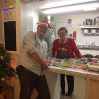 Doris standing in the kitchen with a counter full of food items, with John in front of the counter.