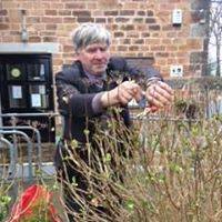 Denny, in front of a plant, weilding pruning shears.